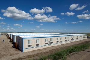 In this Tuesday, July 26, 2011 photo, a man walks back to his temporary housing unit outside of Williston, N.D. With what many are calling the largest oil boom in recent North American history, temporary housing for the huge influx of workers, known as 